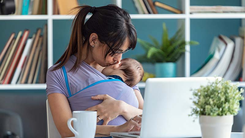 Mãe a dar um beijinho ao bebé junto a um portátil